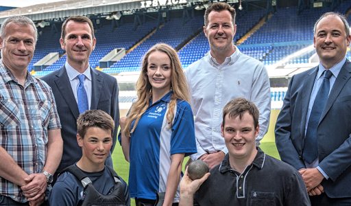 Group of people smiling on football pitch