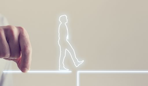 Silhouette of man waling across a bridge held by another man