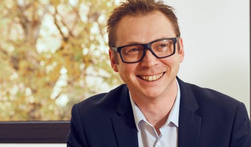 Chris Norton in suit sitting in front of window